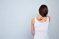 Young woman scratching back on light background