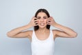 Young woman scratching face on light background.