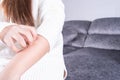 Young woman scratching his arm while sitting on sofa at home. Healthcare medical or daily life concept Royalty Free Stock Photo