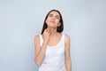 Young woman scratching neck on light background