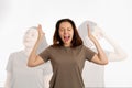 A young woman screams, arms outstretched. On a white background, the shadows of other human personalities. The concept of human