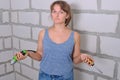 Young woman with screwdriver on wall background. Questions to repair their own hands. How to carry out repairs in the apartment on