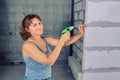 A young woman screws a screw into the wall, copy space. Repairs in the apartment alone. Girl with a screwdriver in his hands Royalty Free Stock Photo
