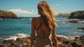 Young woman seen from behind standing looking at the sea during the sunset