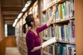Young woman selecting book in library Royalty Free Stock Photo