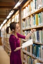 Young woman selecting book in library Royalty Free Stock Photo