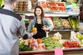 Young woman seller helping customer to buy fruit Royalty Free Stock Photo