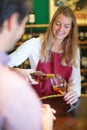 young woman seller serving male client in wine store