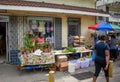 Young woman is standing outside a vibrant fruit market and selling plants