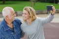 Young woman and senior man doing selfie outdoors