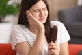 Young woman with sensitive teeth and cold ice cream on sofa at home Royalty Free Stock Photo