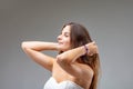 Young woman serenely stroking long brown hair, white dress and b Royalty Free Stock Photo