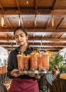 Young woman serves Singapore Sling cocktail at historic Raffles Hotel Bar in Singapore