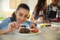 Woman serving food in crowded kitchen. Cooking class Royalty Free Stock Photo