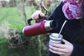 Young woman serving mate in a natural space. Latin beverage.