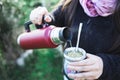 Young woman serving mate in a natural space. Latin beverage.