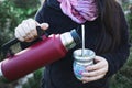 Young woman serving mate in a natural space. Latin beverage.