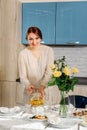 A young woman sets the dining table in the kitchen