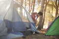 Young woman setting up tent on field