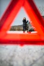 Young woman setting up a warning triangle and calling for assistence