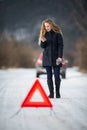 Young woman setting up a warning triangle and calling for assistence