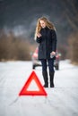 Young woman setting up a warning triangle and calling for assistence Royalty Free Stock Photo