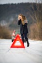 Young woman setting up a warning triangle and calling for assistence