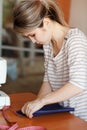 Young woman sewing at home, hemming blue fabric. Fashion designer creating new fashionable styles. Dressmaker makes clothes via ad