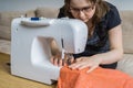 Young woman is sewing textile with sewing machine