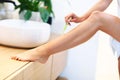Young woman shaving legs in bathroom Royalty Free Stock Photo