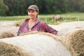Young woman in shirt and cap smiling, hay stack rolls near her Royalty Free Stock Photo