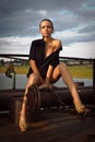 Young woman only in shirt, high heels, long legs. Metal structures, dramatic sky. fashion style