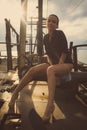 Young woman only in shirt, high heels, long legs. Metal structures, dramatic sky. fashion style