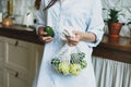 Young woman in shirt hold knitted rag bag shop with avocado and green apples in hands on the kitchen