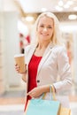 Young woman with shopping bags and coffee in mall Royalty Free Stock Photo