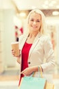 Young woman with shopping bags and coffee in mall Royalty Free Stock Photo