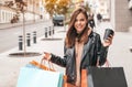 Young woman with shopping bags and coffee walking outdoors. Happy lifestyle, holiday discounts and sales