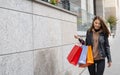 Young woman with shopping bags walking on the street. Good mood, holiday discounts, sales concept.