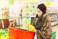 Young woman with shopping basket choosing paprika bell pepper during shopping at the supermarket. Shopping concept. Royalty Free Stock Photo