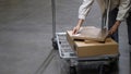 Young woman with shopping cart walking for choosing new furniture in big store warehouse and put some boxes in trolley