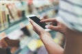 Young woman shopping healthy food in supermarket blur background. Close up view girl buy products using smartphone in store