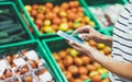 Young woman shopping healthy food in supermarket blur background. Female hands buy nature products using smart phone in store Royalty Free Stock Photo