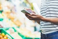Young woman shopping healthy food in supermarket blur background. Female hands buy nature products using smart phone in store Royalty Free Stock Photo