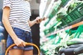 Young woman shopping healthy food in supermarket blur background. Female hands buy products and using mobile smart phone in store Royalty Free Stock Photo