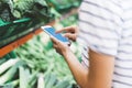 Young woman shopping healthy food in supermarket blur background. Female hands buy products and using mobile smart phone in store Royalty Free Stock Photo