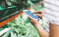 Young woman shopping healthy food in supermarket blur background. Female hands buy products and using mobile smart phone in store Royalty Free Stock Photo