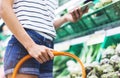 Young woman shopping healthy food in supermarket blur background. Female hands buy products and using mobile smart phone in store Royalty Free Stock Photo