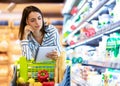 Young woman with shopping list in supermarket Royalty Free Stock Photo