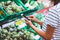 Young woman shopping purchase healthy food in supermarket blur background. Close up view girl buy products using smartphone in sto Royalty Free Stock Photo