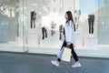 Young woman while shopping walks past shop windows with bags in her hands. Exhausting shopping